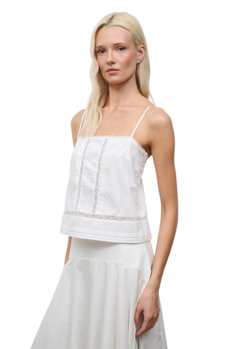 A close-up of a woman wearing an ivory sleeveless top and a midi skirt set