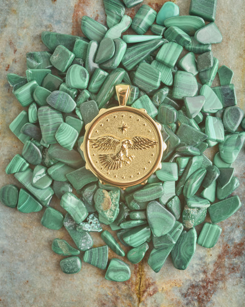 Gold pendant with eagle design on a bed of green stones