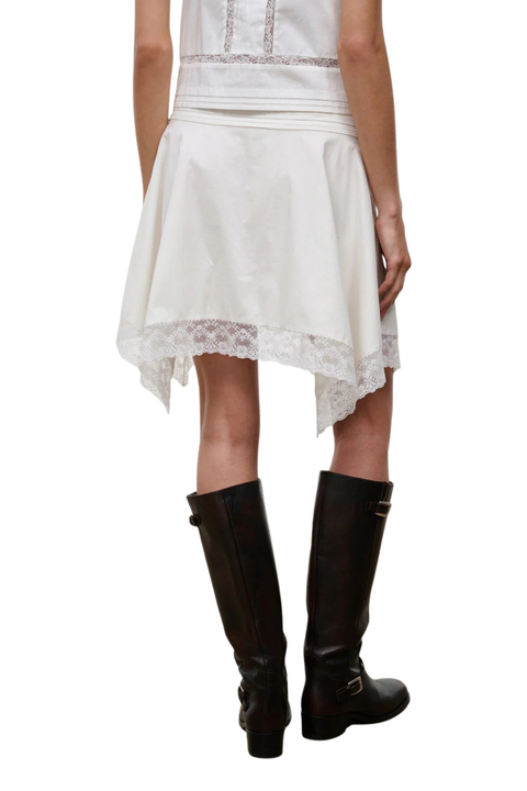A woman wearing a white lace midi skirt with a matching white sleeveless top close-up