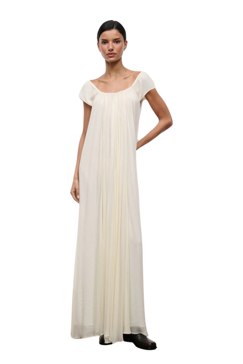 A woman wearing a long ivory dress with short cap sleeves and an elastic neckline