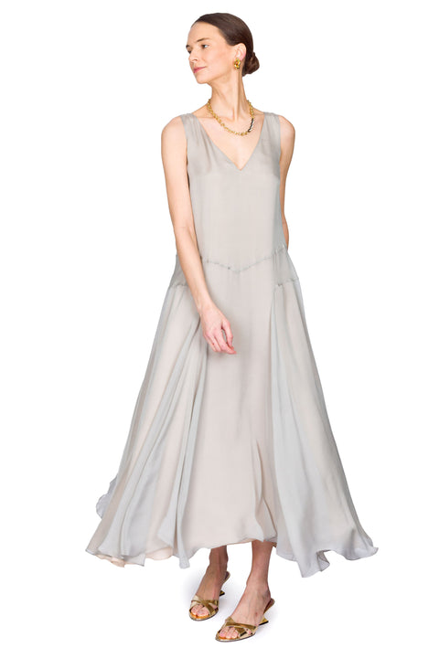 Woman twirling in wearing Kallmeyer light gray sleeveless dress on a white background