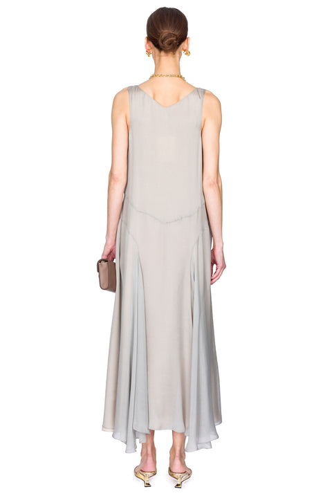 Woman showing back of a light gray sleeveless dress on a white background