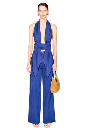 A woman wearing cobalt blue denim jeans with a matching blue jersey halter top with drapery