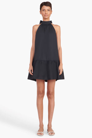 Full body view of a model facing the camera in the black high neck mini dress
