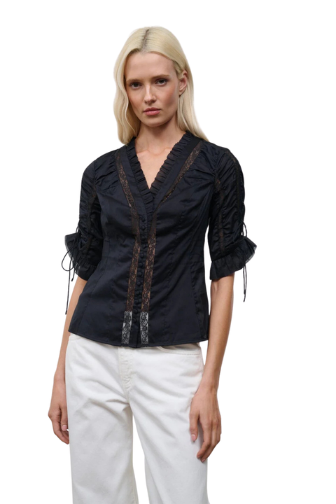 A woman wearing a black button-up top with cinched sleeves and lace detailing