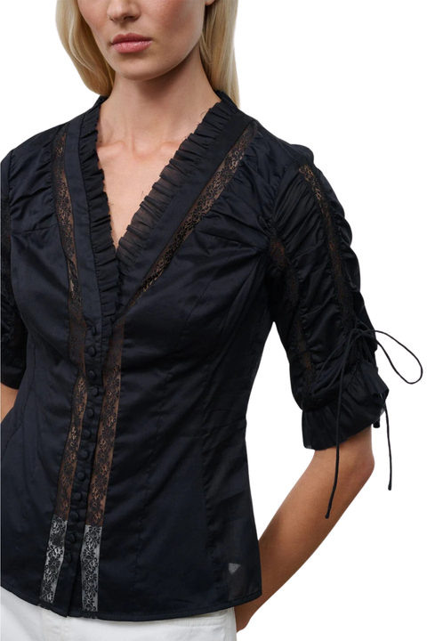 Close-up of a woman wearing a black button-up top with cinched sleeves and lace detailing