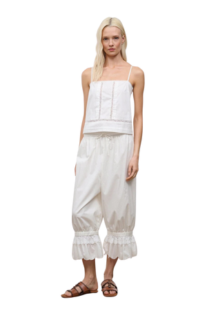 A woman wearing ivory bubble cropped trousers with an embroidered lace hem