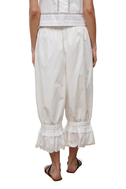 Back angle of a woman wearing ivory bubble cropped trousers with an embroidered lace hem