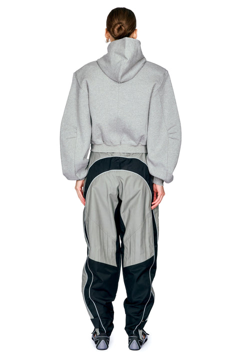 A model shown from the back wearing a light gray cropped hoodie and matching gray and black pants with white piping details, set against a plain white background.