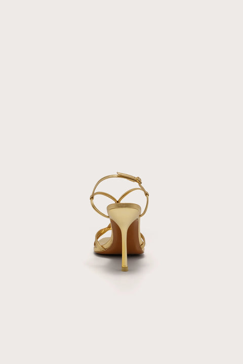 Back-facing strappy gold stiletto heel that features gold-toned bamboo hardware. 