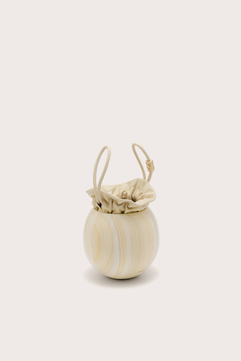 A spherical handbag made of marbles yellow acrylic with an inner pouch that sinches closed and two matching handles. 
