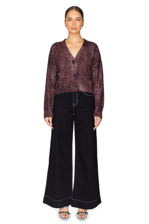 Woman wears metallic purple knit cardigan with black denim.