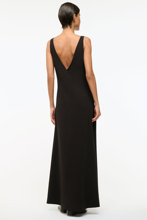 Back view of a woman wearing a black maxi dress that features a deep-v open back. 