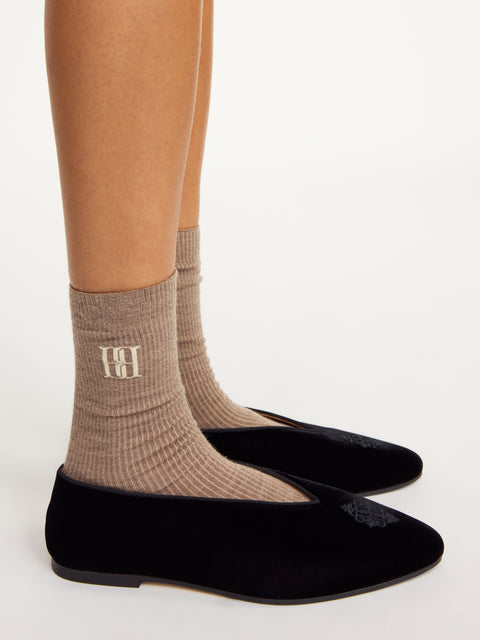 Woman wears brown logo socks with velvet shoes.