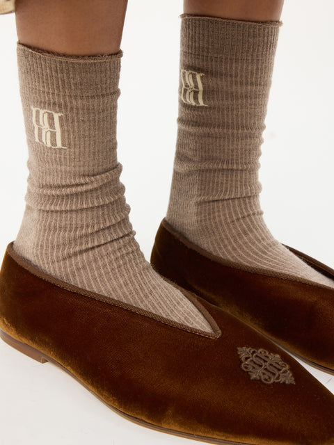 Up close of woman wearing the brown logo socks and brown velvet shoes.