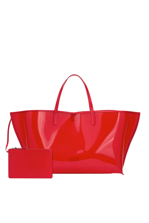 A bright red glossy patent leather tote bag with matching red shoulder straps and a small rectangular red pouch placed in front, shown on a plain white background.