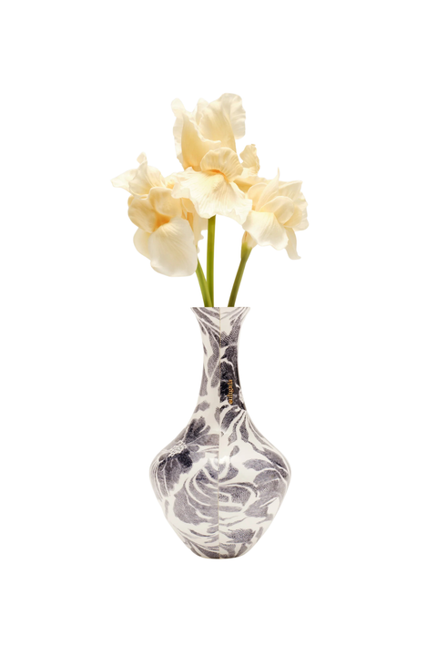 A small bulb-shaped vase with a black and white marbled pattern, holding three pale cream-colored flowers with green stems, isolated on a white background.