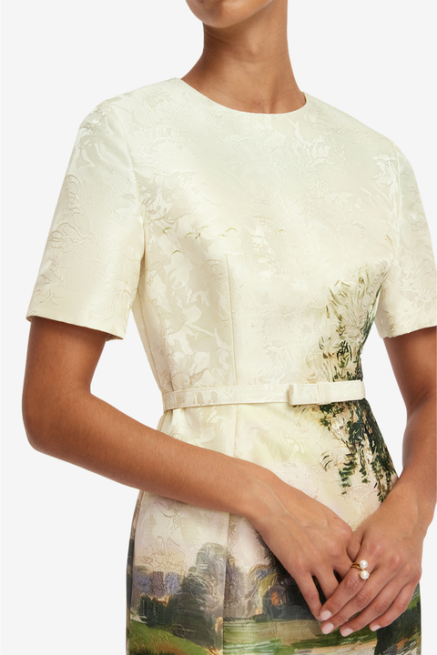 Woman wearing a cream-colored dress with floral pattern on a white background