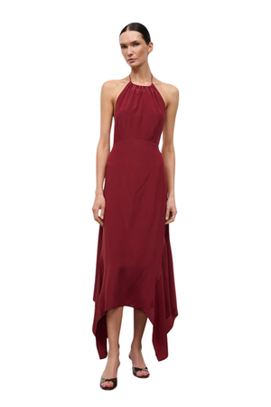 A woman in a sleeveless halter-neck maxi dress in deep burgundy, photographed against a solid white background.