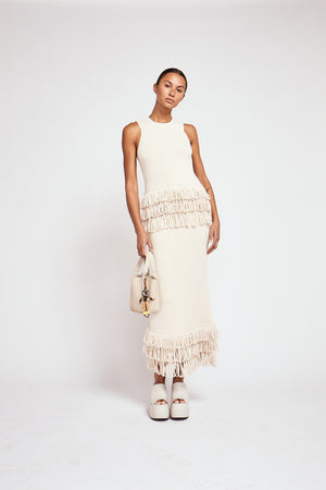Model facing the camera in the ecru Hartland top with layered fringe hem and paired with a matching skirt