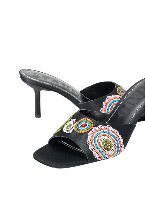Black satin mule sandals with a high stiletto heel and colorful beaded paisley embellishments on the strap, shown against a plain white background.
