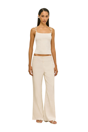 Woman wearing a beige sleeveless top with pearl embellished straps front angle