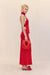Side view of a woman wearing a bright red silk maxi skirt in a flattering bias cut, styles with a red top and red accessories. 