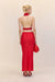 back view of a woman wearing a bright red silk maxi skirt in a flattering bias cut, styles with a red top and red accessories. 