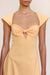 Detail shot of a woman wearing a bright orange maxi dress that features cap sleeves, a sweetheart neckline, and a delicate chest cutout with a twist knot detail. 