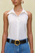 Up close of a woman wearing a white sleeveless, button down, collared bodysuit paired with blue denim shorts and a black belt. 
