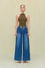 Woman wearing an olive green sleeveless bodysuit that features a mock neck, paired with blue wide leg jeans. 
