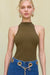 Up close of a woman wearing an olive green sleeveless bodysuit that features a mock neck, paired with blue wide leg jeans. 