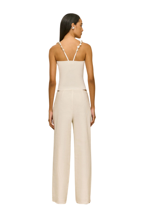 Woman wearing a beige sleeveless top with pearl embellished straps back angle