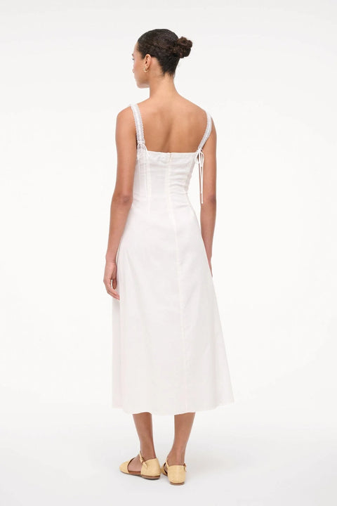 Back-facing woman wearing a white midi dress. 
