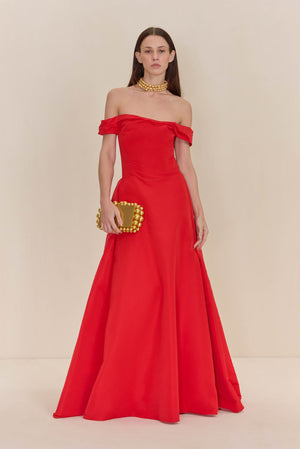 Woman wearing a bright red, floor length gown that features an off-the-shoulder neckline and a voluminous skirt. 