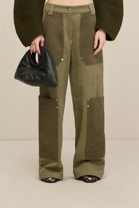 Close up of a woman wearing green two-tone cargo pants with a green structured top. 