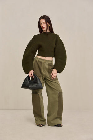 Woman wearing green two-tone cargo pants with a green structured top. 