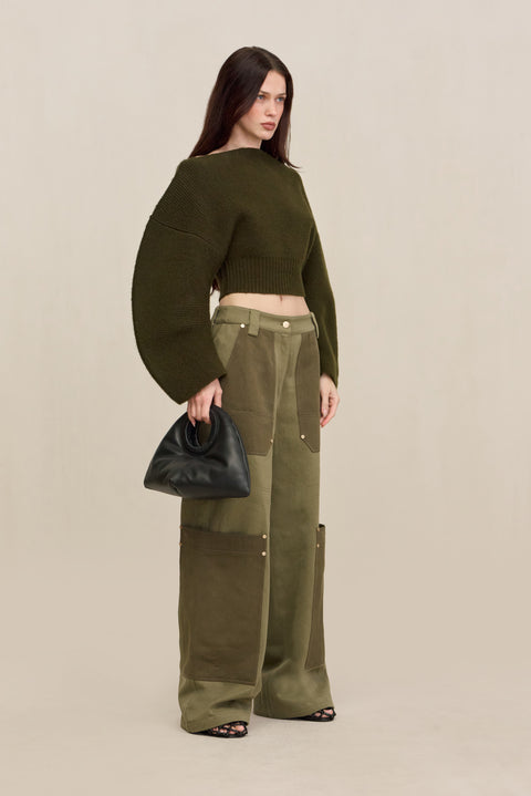 Side-facing woman wearing green two-tone cargo pants with a green structured top. 