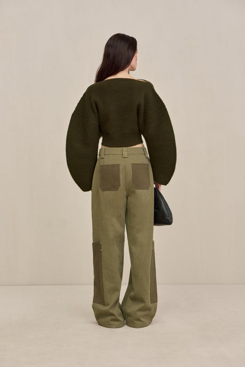 back-facing woman wearing green two-tone cargo pants with a green structured top. 