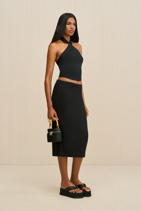 Woman wearing a black halter top and skirt set with a beige background