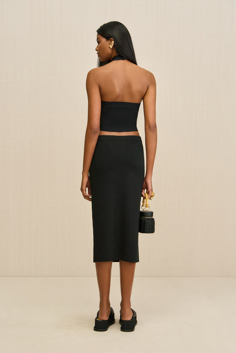 Woman wearing a black strapless top and skirt set with a beige background