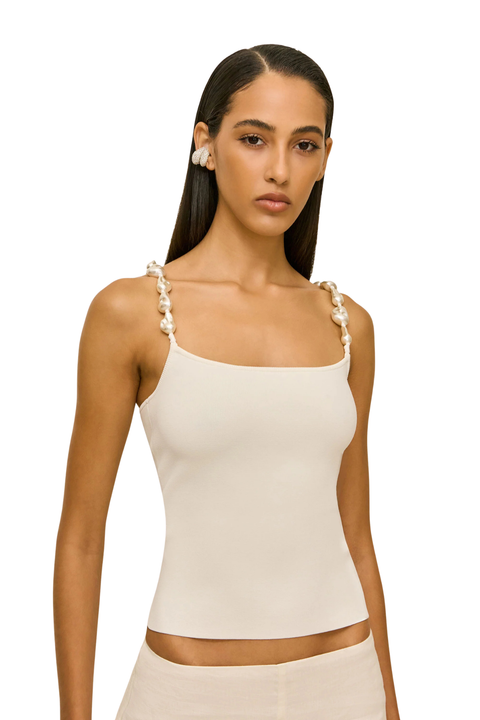 Woman wearing a beige sleeveless top with pearl embellished straps close up angle