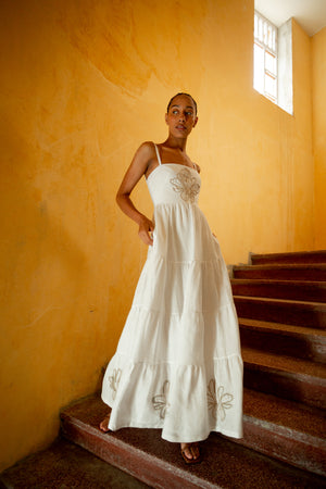 Model posing on staircase in the off white tiered maxi dress.