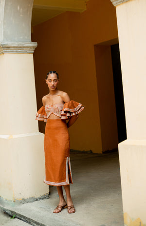 Model styled in the orange habana midi skirt with side slits.