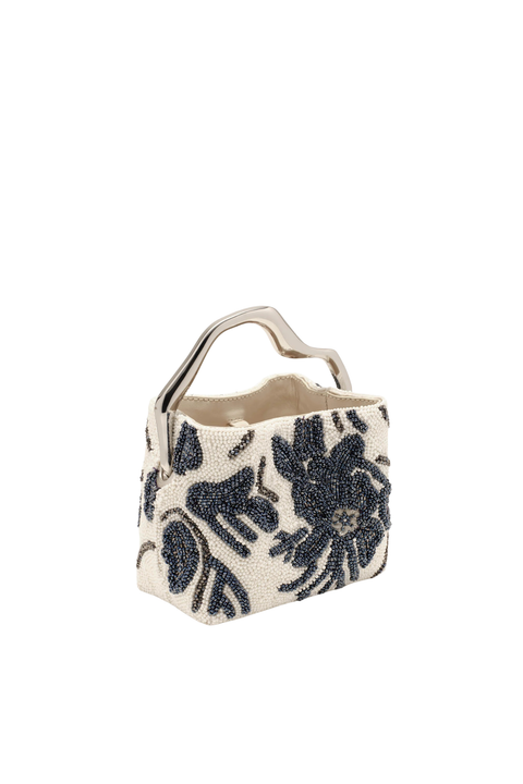 A small structured handbag with a cream base and large black floral beaded pattern, featuring a curved silver-tone metal handle, shown on a plain white background.