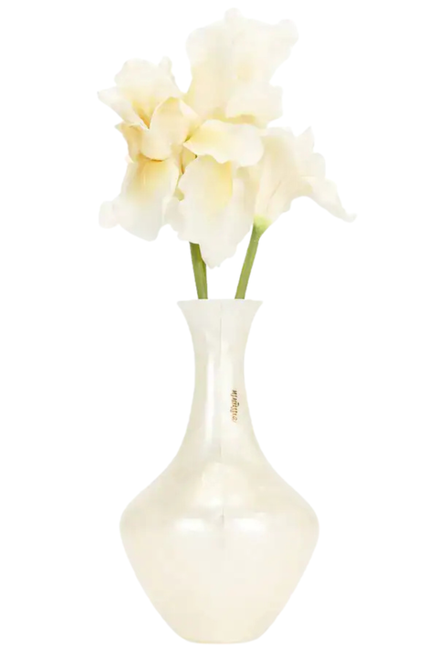 A glossy white ceramic vase clutch with a small gold emblem, holding three white iris flowers with green stems, isolated on a white background.