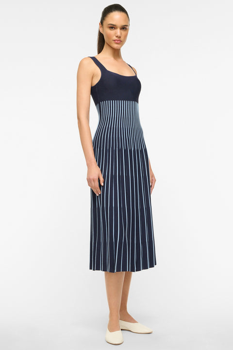 Side view of a woman wearing a navy and light blue striped knit midi dress. 