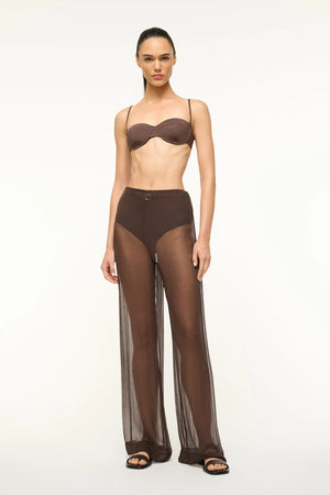 Woman wears sheer brown pants with bra top.