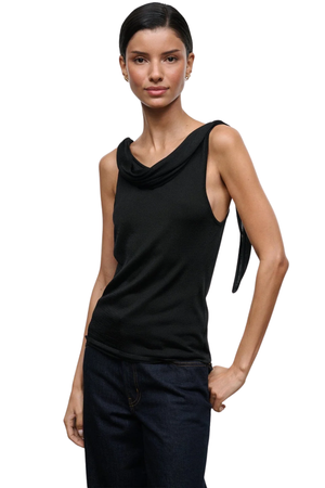 A model wearing a black sleeveless cowl-neck top with a side tie detail, paired with dark blue jeans, against a plain white background.