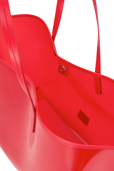 A close-up of a glossy bright red tote bag showing the interior lining, handle attachment, and a small interior label, isolated on a white background.